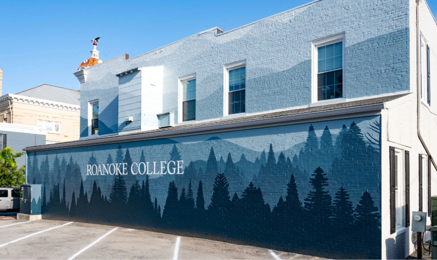 Two-story mural depicting ombre layers of blue mountains with blue trees at the bottom.