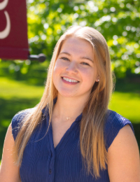 Head shot of young woman with blonde hair in a sleeveless blue blouse