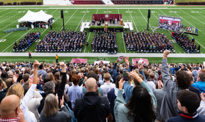 Family and friends cheer in the stands as graduates take their seats on the field at Salem Stadium.