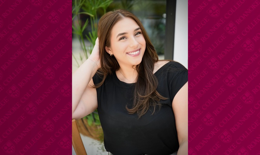 A portrait of Kathryn, a woman with long dark brown hair. She is wearing a black shirt and smiling at the camera. There is a maroon Roanoke College border on either side of the photo. 