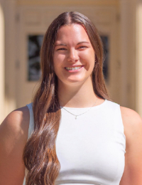 Headshot of young woman with long brown hair in white sleeveless top