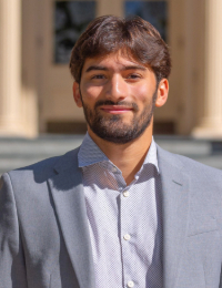 Headshot of dark-haired young man in a gray suit