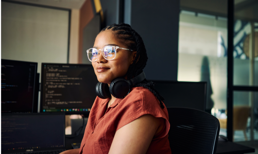 A woman who's been working at a computer turns and smiles for a photo