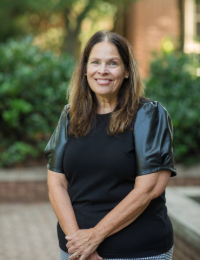 headshot of a woman in a black blouse with black leather sleeves