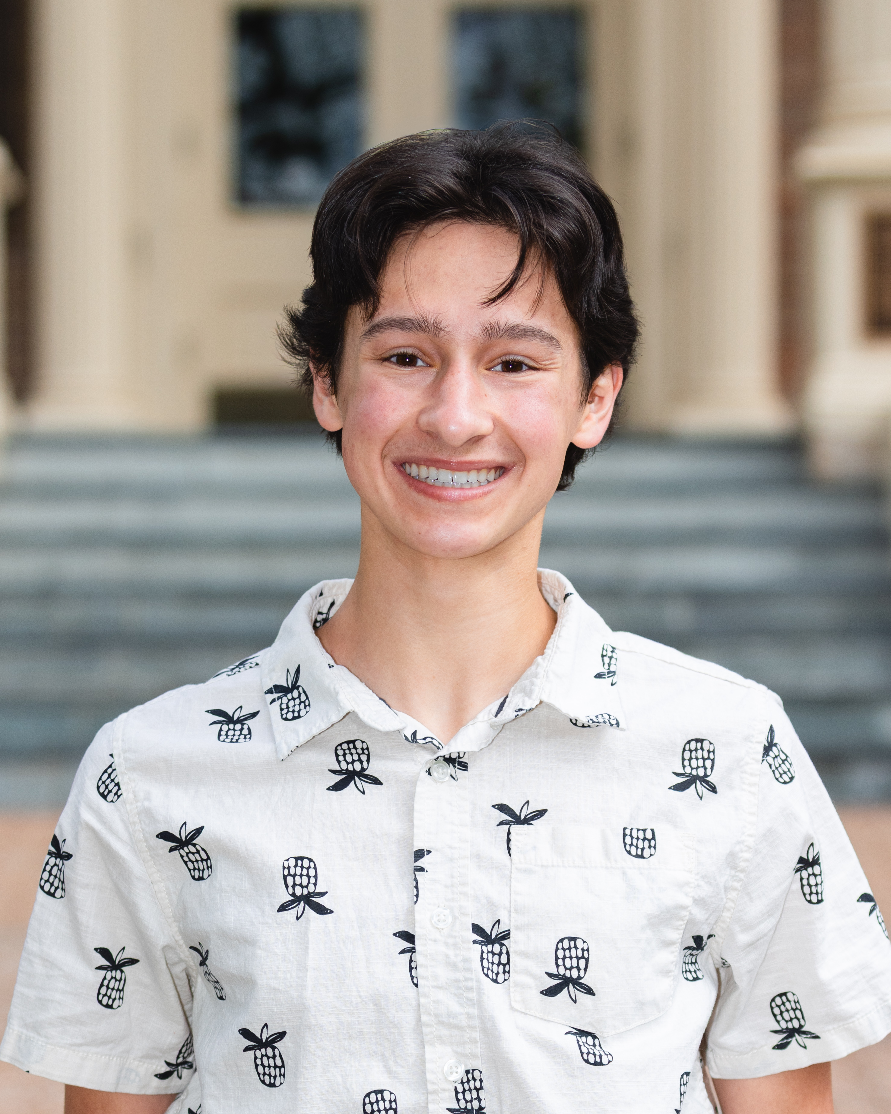 Headshot of young man with dark hair in a white shirt.