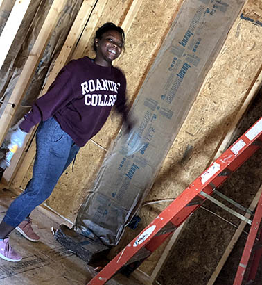 A student smiling for a photo next to the boards she's working on