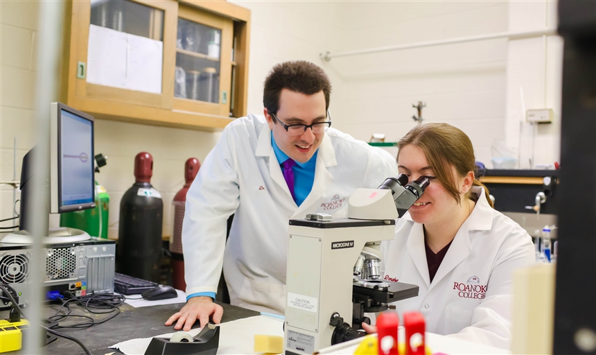 Student looking through microscope with professor in the chemistry lab