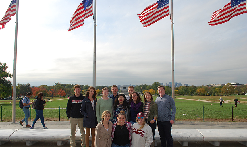 Students from the DC Semester program stand in front of American flags in front of the Lincoln Memorial