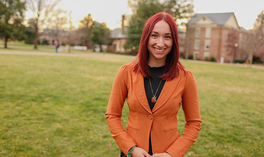 young woman stands in front of brick building