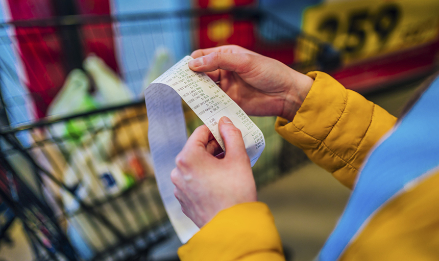 Someone checks a receipt with shopping cart in the background