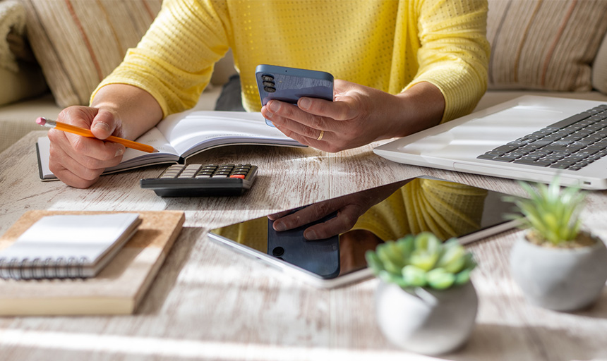 Closeup of a woman's hands working with a calculator and budgeting documents