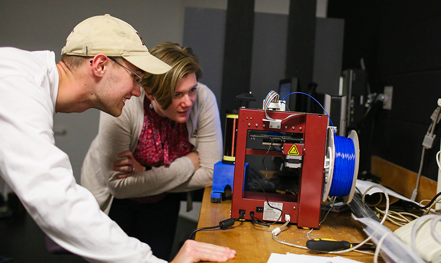 Lambert and a professor work with lab equipment