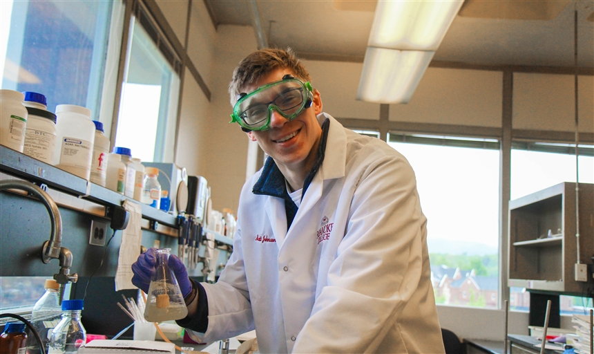 Matthew Johnson holding a beaker while conducting research