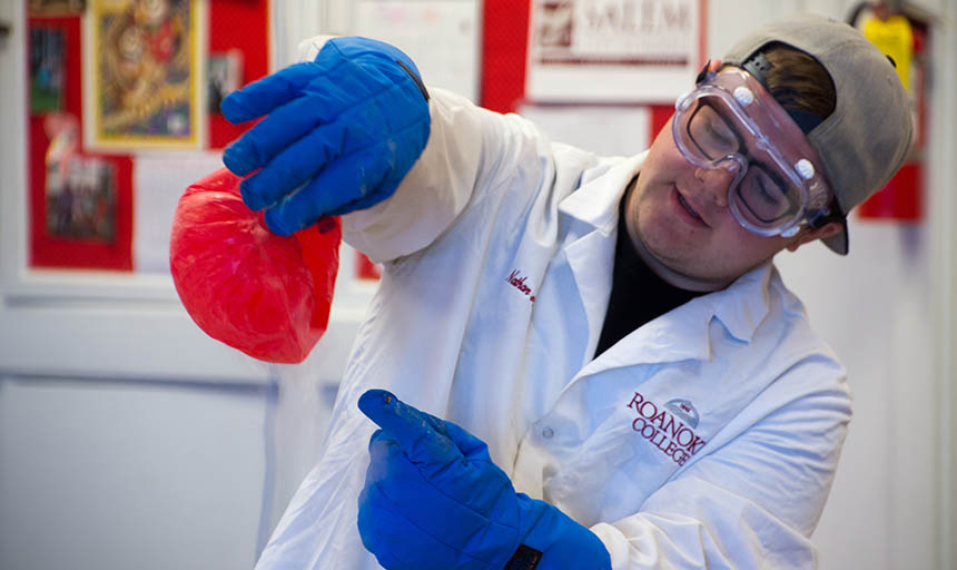 A student in a lab coat helps conduct an experiment