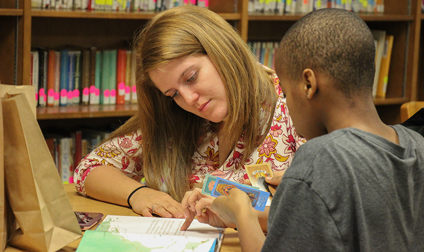 Student education major works with elementary student