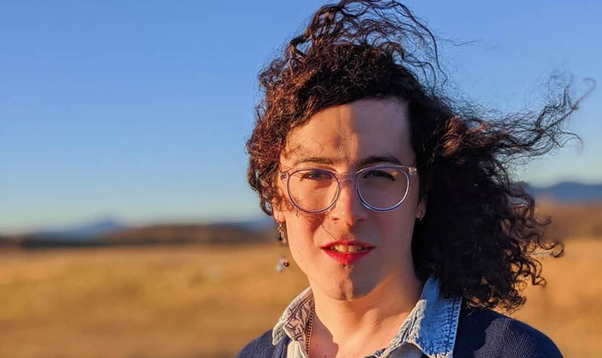 Woman with wind-blown hair poses for a photo outside.