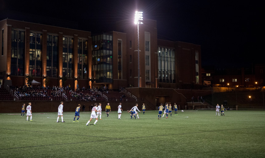 Men's soccer team playing outside at night under the lights