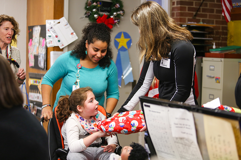 Student in wheelchair receiving gift from RC student with aid.