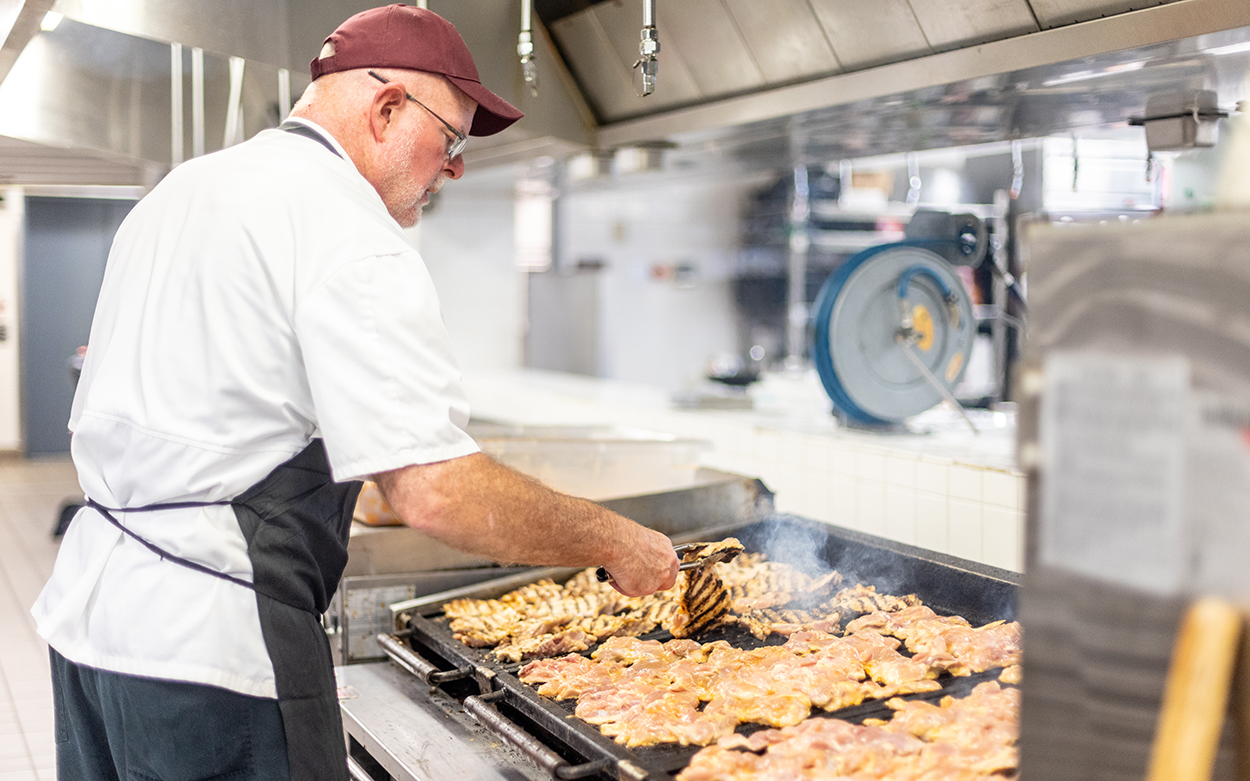 A Dining Services employee grills fresh chicken for the daily meal.