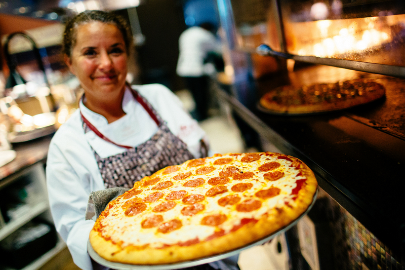 Kitchen staff holding a pizza
