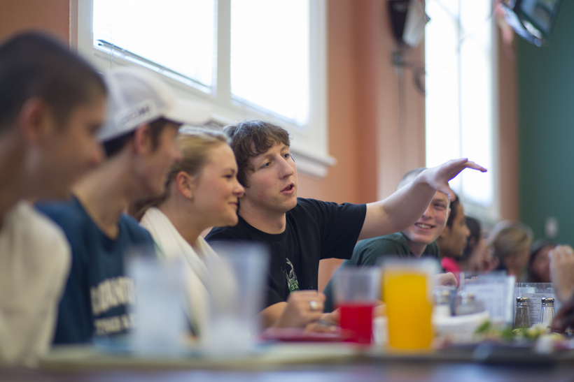 Students talking and eating in The Commons by the windows