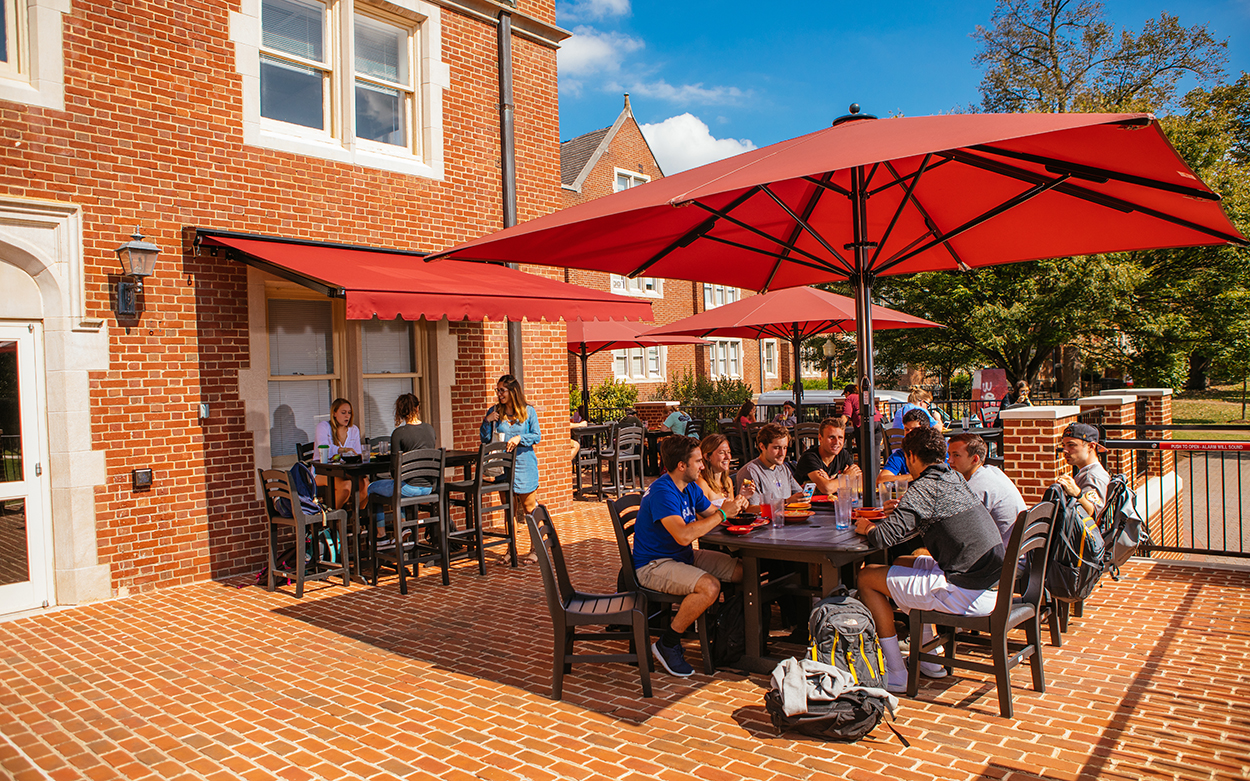 Students dine under red umbrellas on the Sutton patio.