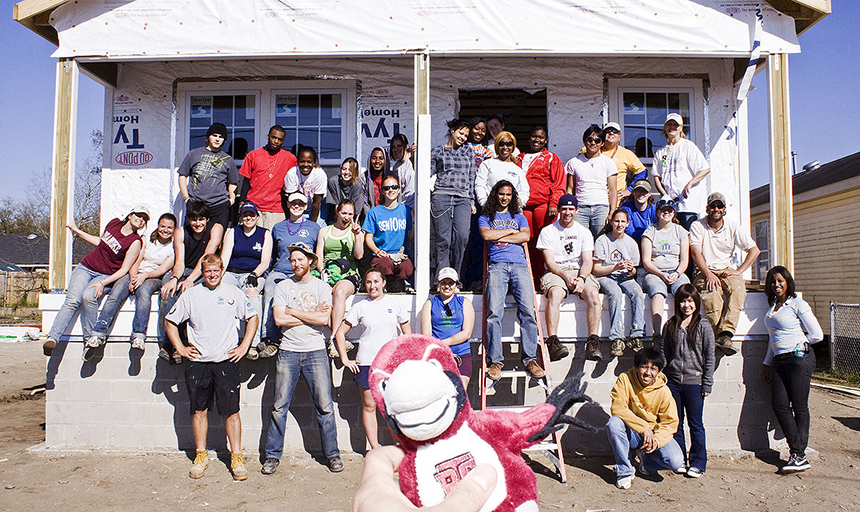 Students posing by a mostly-finished home that they built in New Orleans