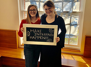 Students posing by the" make interfaith happen" sign