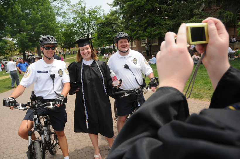 Campus safety posing with a senior in her graduation cap and gown