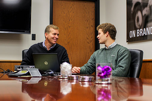 Two alumni talking at a conference table
