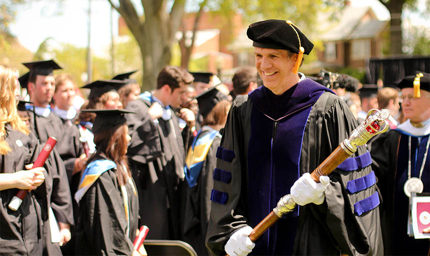 Prof. Chris Lee holding academic mace at graduation