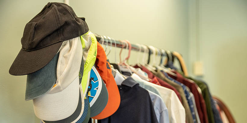 Closeup of a rack of clothing on hangers and a stack of hats