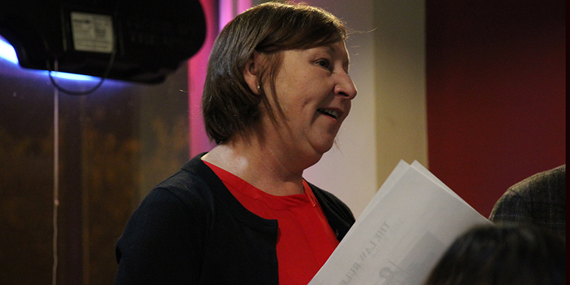 Woman with red shirt and black sweater holding papers