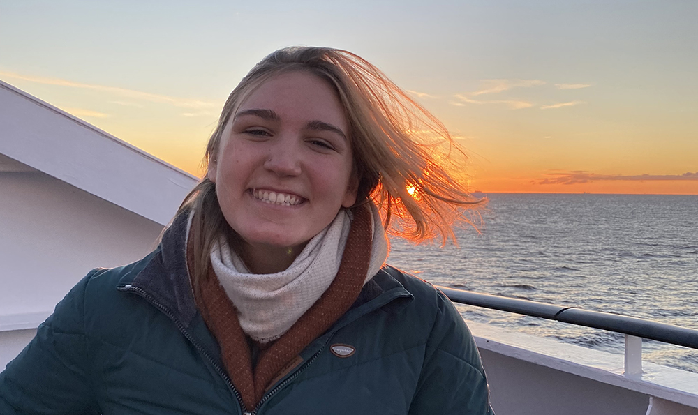 young woman smiles on boat at sunset