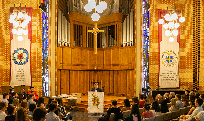 A crowd is seated in Antrim Chapel as Dr. Peter Hotez speaks from podium in the center