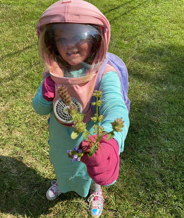 girl holding flowers wearing protective hat with face shield and fan