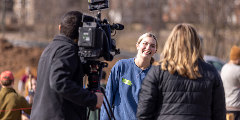 A student volunteer is interviewed by a local TV news crew