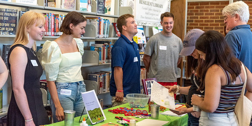 Students lined up at a table smile while greeting guests at the Salem Public Library where their books were unveiled