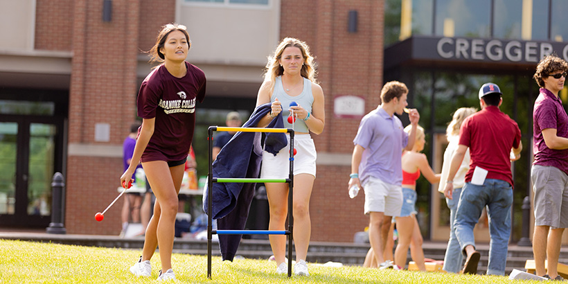 One students looks on while another winds up for a throw in a game of ladder toss