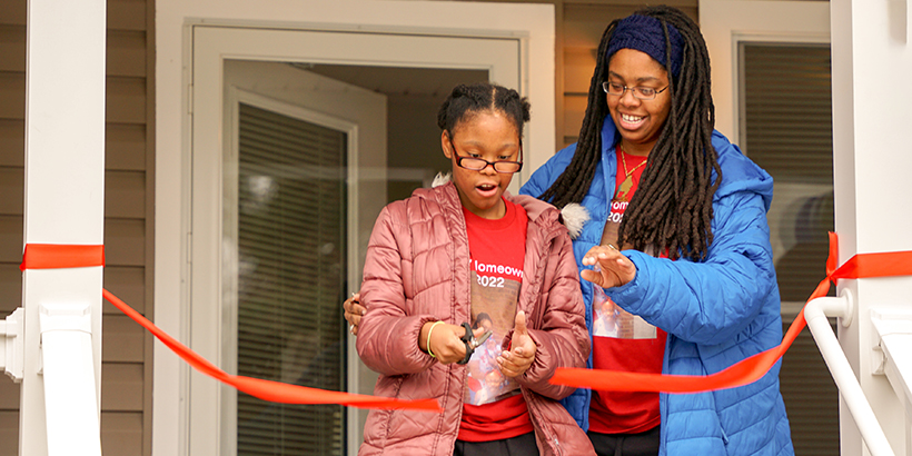 Homeowner and daughter cut the ribbon to their new home