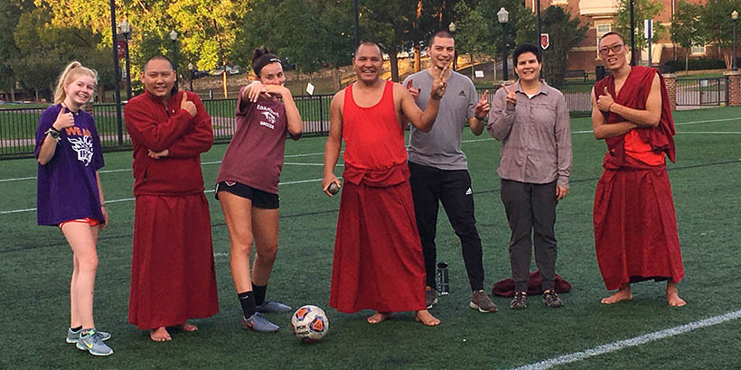 The Tibetan Monks posing for a photo with members of the women's soccer team