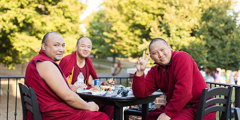The Tibetan Monks eating outside and smiling at the camera