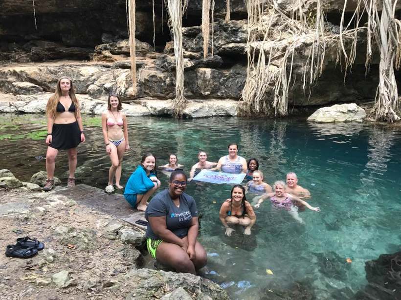 Students at a natural water pool with a Roanoke College banner