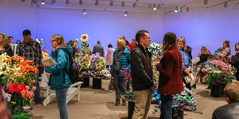 View of the gallery reception, flowers and people