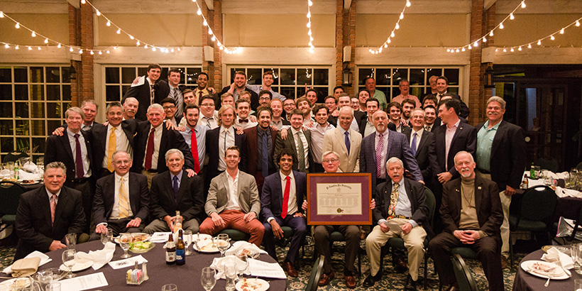 Pi Lambda Phi members and alumni members holding the recharter document at their recharter celebration