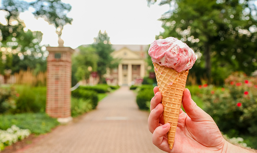 Someone holding an ice cream cone in front of campus.