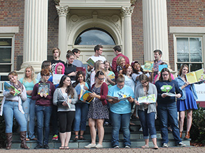 Students pose for a group photo reading or holding up various books