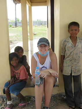 Student sitting with children in Cambodia