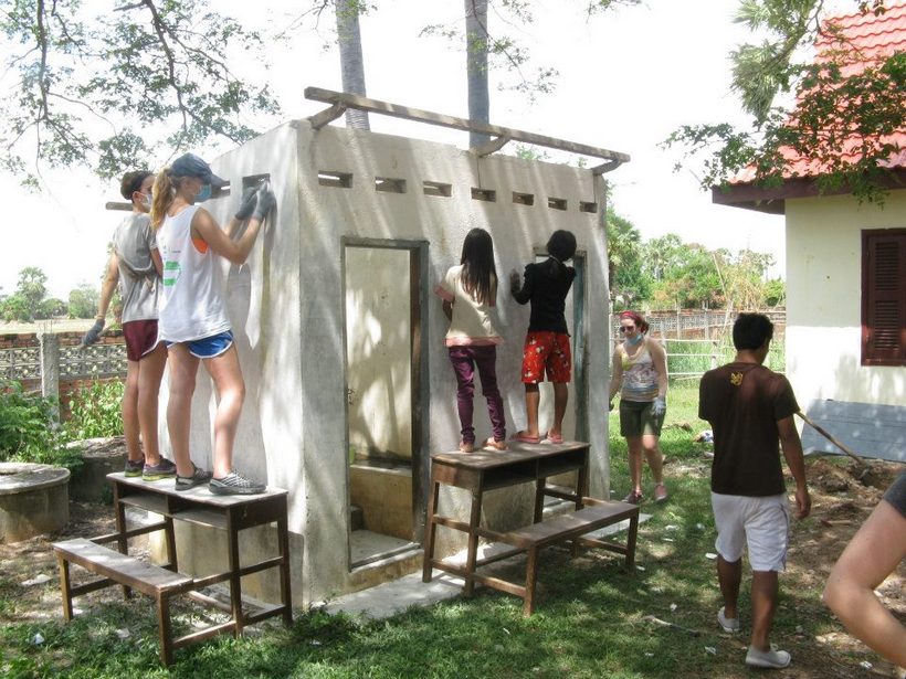 Student working on a structure with children in Cambodia