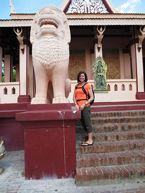 Student posing by a statue of a lion in Cambodia